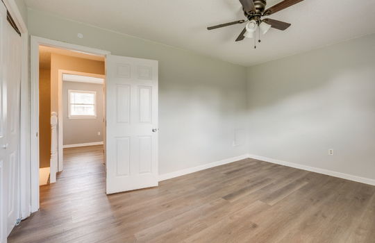 bedroom, door to hallway, vinyl flooring, ceiling fan