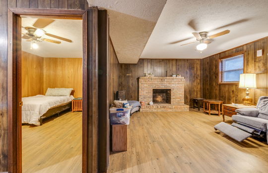 lower level den, lower level bedroom, paneling walls, ceiling fans, hardwood flooring, brick fireplace, window