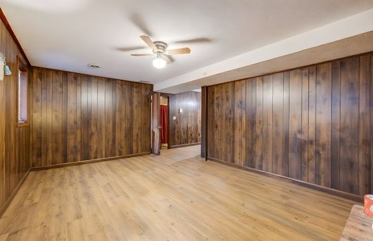 lower level den, digitally altered to remove furniture, paneling walls, ceiling fan, view toward foyer stairs
