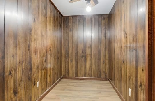 lower level bedroom/bonus room, hardwood flooring, ceiling fan, digitally altered to remove furniture, paneling walls