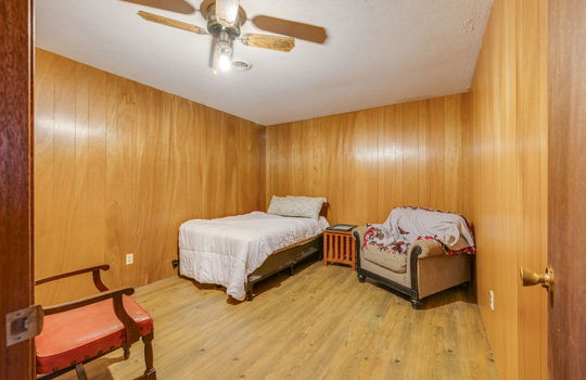 lower level bedroom, hardwood flooring, paneling walls, ceiling fan
