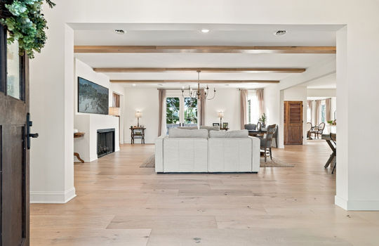 main level living room, fireplace, ceiling beams, hardwood flooring, double doors, front door