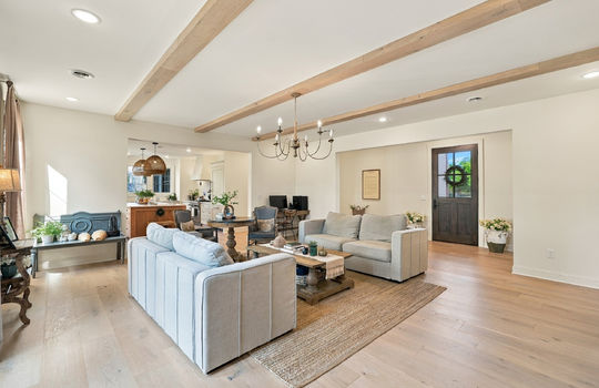 living room, ceiling beams, hardwood flooring, view into kitchen, front door/foyer