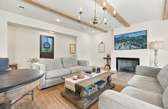 living room, view into foyer/front door, ceiling beams, fireplace, hardwood flooring