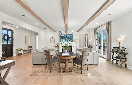 living room, ceiling beams, double doors to exterior, front door, hardwood flooring, recessed lighting, fireplace