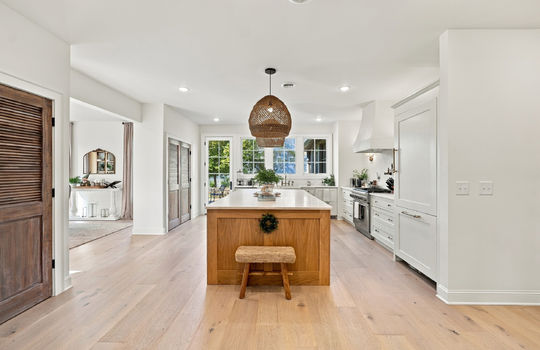 kitchen, kitchen island, hardwood flooring, pantry, cabinets, marble countertops, refrigerator, stainless gas range, windows, apron sink, exterior door to outside