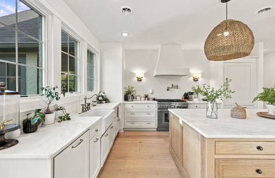 kitchen, oversized kitchen island, marble countertops, gas range, refrigerator, apron sink, windows, pot filler faucet