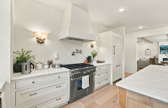 kitchen, island, hardwood flooring, marble countertops, cabinets, refrigerator, gas range, pot filler faucet