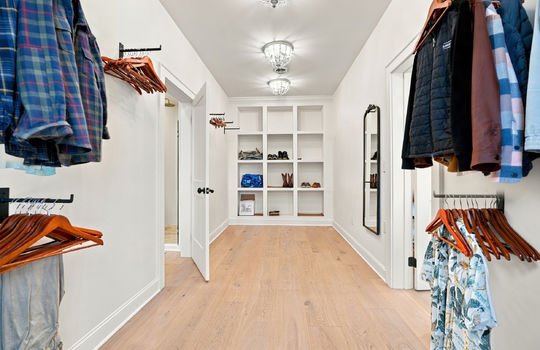 Primary bedroom walk-in closet, built in shelving, hardwood flooring,