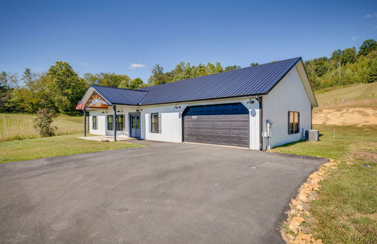 right side view of home, driveway, garage, metal siding, metal roof, covered front porch, double door entry door, front door, front yard, side yard, back yard