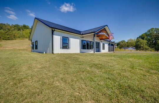 left side view of home, farmhouse, barndominium, metal siding, metal roof, covered front porch, driveway, garage, front yard, side yard, back yard