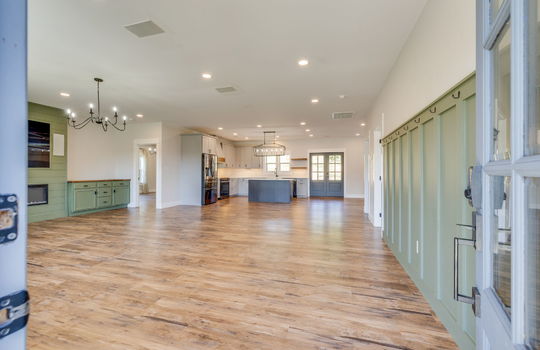 front door view of interior, front door, entryway, open floorplan, living room, luxury vinyl flooring, fireplace, kitchen, kitchen island, kitchen appliances, refrigerator, oven/range, sink, double door exterior door, recessed lighting