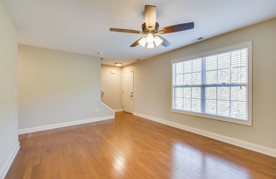 living room, hardwood flooring, ceiling fan, windows, front door, stairs