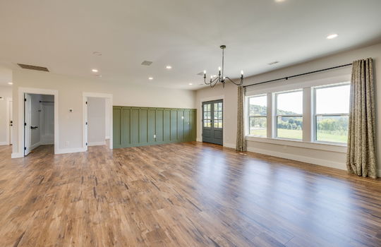 living room, luxury vinyl flooring, front door, windows, recessed lighting, doors to bathroom, and bedroom