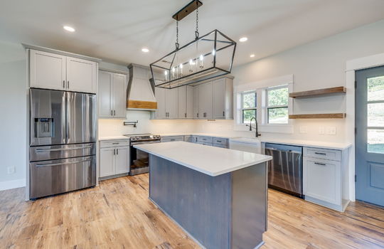 kitchen, kitchen island, dishwasher, oven/range, pot filler faucet, refrigerator, sink, farmhouse sink, cabinets, countertops, luxury vinyl flooring, double doors to exterior, windows above sink, built in shelving, recessed lighting