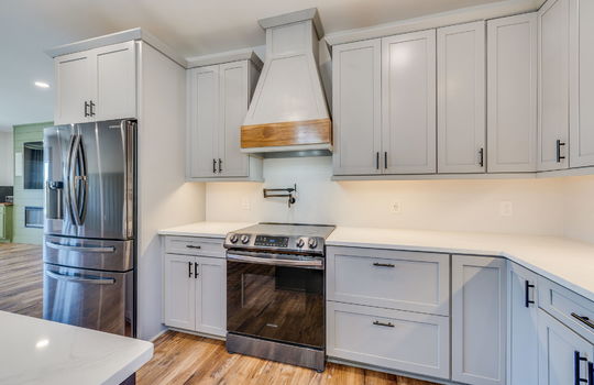 kitchen, stainless appliances, refrigerator, oven/range, pot filler faucet, cabinets, under cabinet lighting, quartz countertops, luxury vinyl flooring