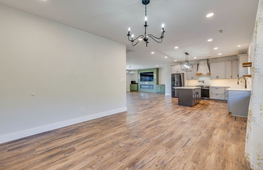 dining space view toward kitchen and living room, luxury vinyl flooring, windows, recessed lighting, kitchen island