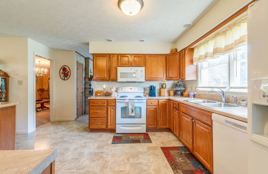 kitchen, laminate flooring, cabinets, countertops, oven/range, built-in microwave, dishwasher, sink, refrigerator, door way to living room and family room