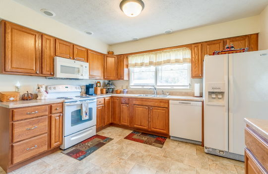 kitchen, laminate flooring, cabinets, countertops, built-in microwave, oven/range, sink, dishwasher, refrigerator, window above sink, recessed lighting