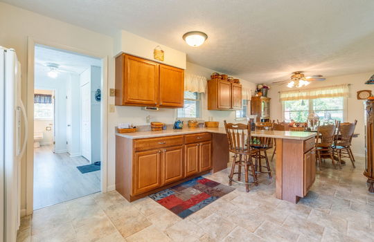 kitchen view into dining area, bar seating cabinets, countertops, dining area, laminate flooring, ceiling fan, windows