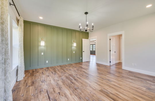 primary bedroom, board and batten feature wall, chandelier, door to kitchen, door to walk-in closet/ensuite bath, luxury vinyl flooring
