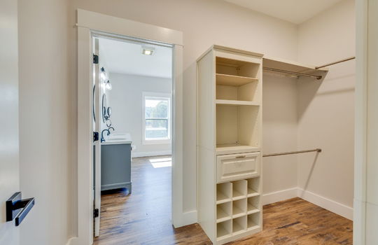 walk in closet space, built-in closet storage, luxury vinyl flooring, door into primary ensuite bathroom