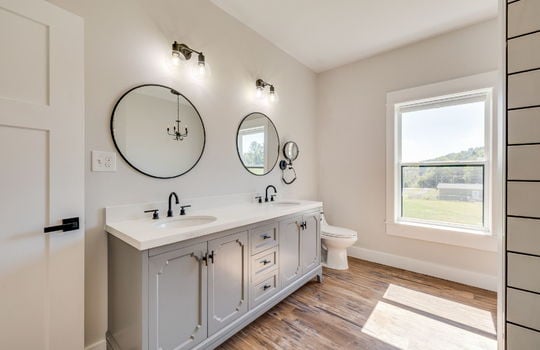primary ensuite bathroom, luxury vinyl flooring, double sink vanity, toilet, window