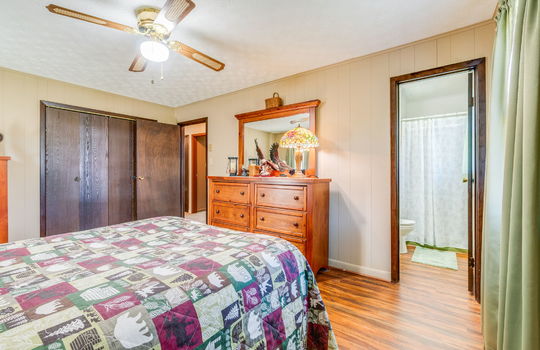primary bedroom, closet, ceiling fan, painted paneling walls, laminate flooring, doorway to ensuite bathroom