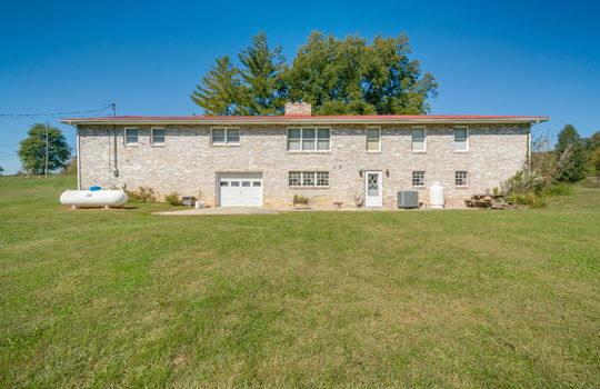 back of home, brick ranch, garage, garage door, entryway door, back yard, trees, landscaping