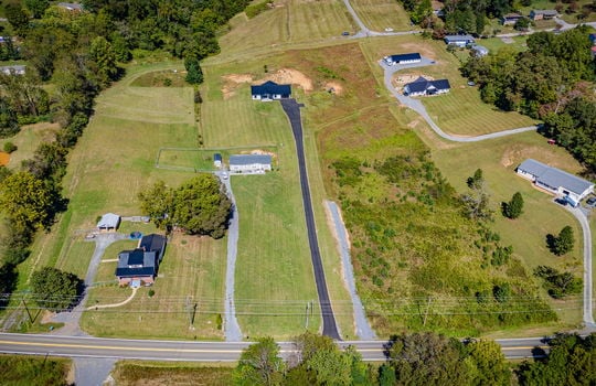 aerial view of home, driveway, barndominium, neighboring homes, road, trees