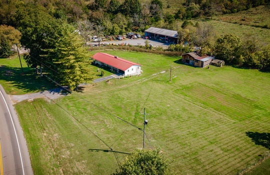 aerial photo of home, brick ranch, road, driveway, metal roof, barn, yard, neighboring homes