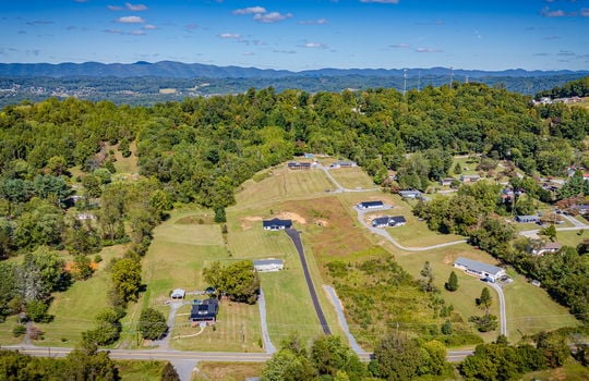aerial view of home, driveway, neighboring homes and driveways, road, trees, mountain views