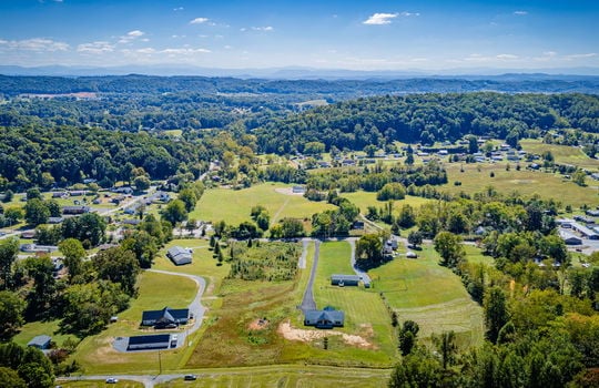 aerial view of home, driveway, neighboring homes and driveways, road, trees, mountain views