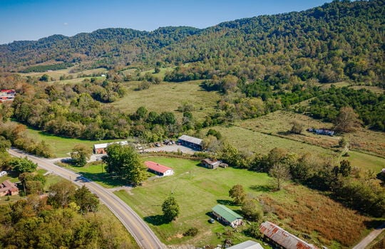 aerial photo of home, road, front yard, trees, metal roof, back yard, barn, mountain views, neighboring properties