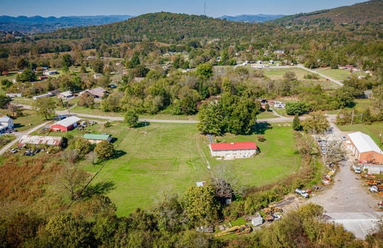 aerial photo of home, road, front yard, trees, metal roof, back yard, barn, mountain views, neighboring properties