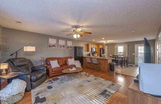 living room, laminate flooring, kitchen, ceiling fan