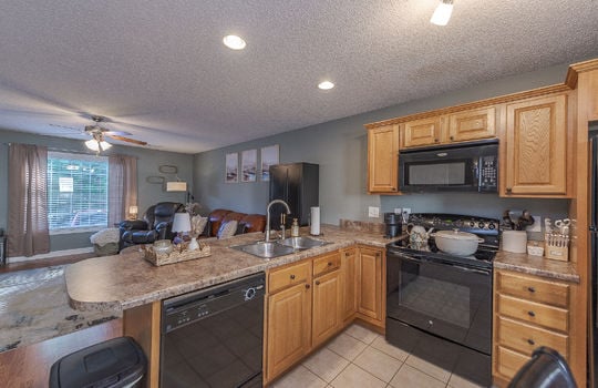 kitchen, dishwasher, sink, oven/range, built-in microwave, cabinets, countertops, tile flooring, view toward living room, open concept
