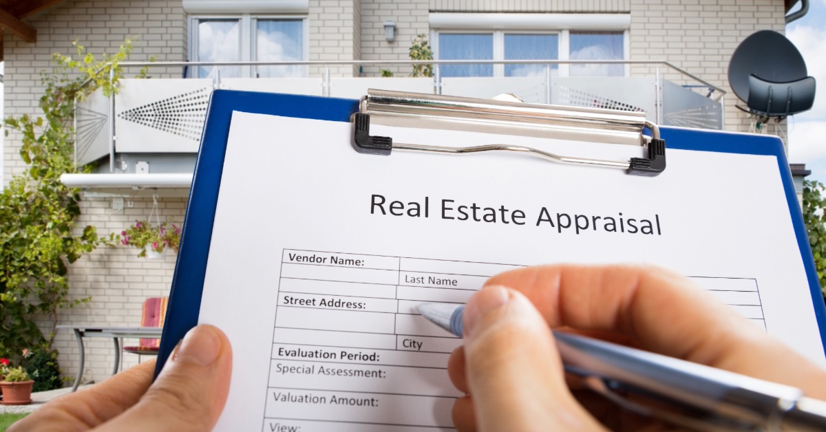 A person's hand filling out a real estate appraisal document.