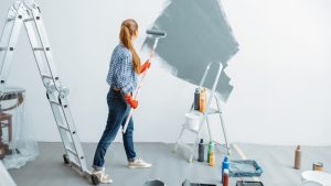 a woman painting the wall with ladder on the side and some tools for painting