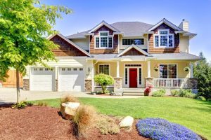 Large American beautiful house with red door and two white garage doors.