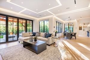 Open concept living room with fireplace wooden beams black door frames and autumn colors
