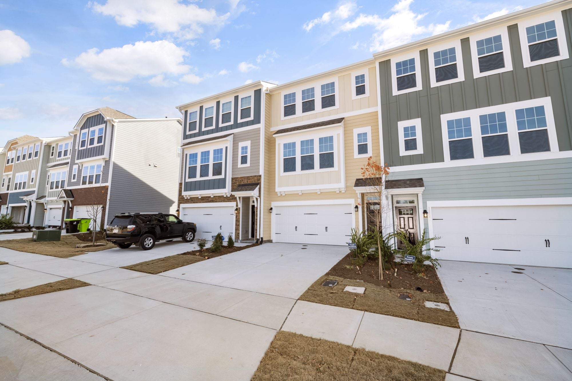 A row of modern townhomes in a suburban neighborhood on a sunny day