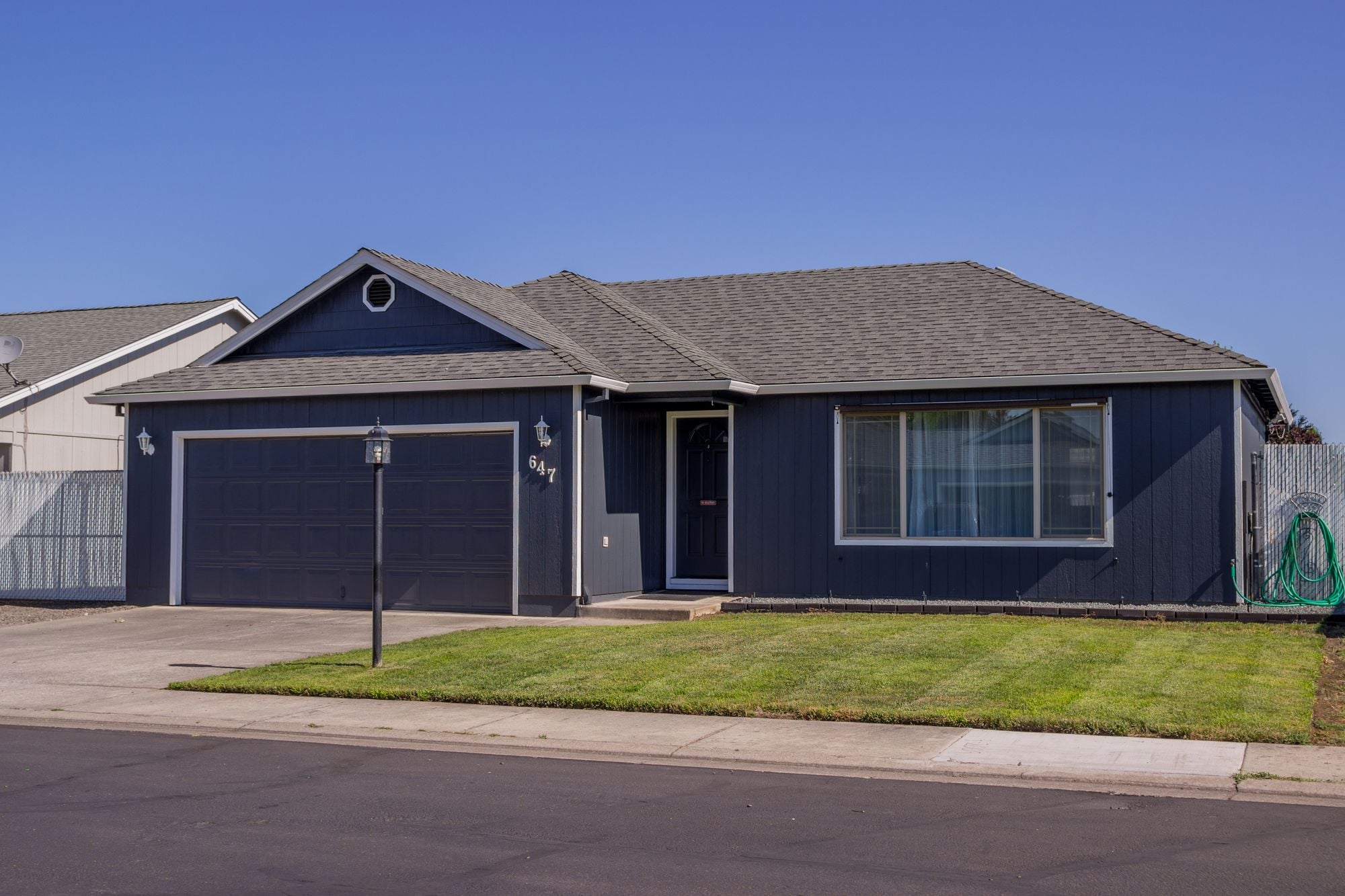 A suburban house with a driveway, garage and a well kept lawn