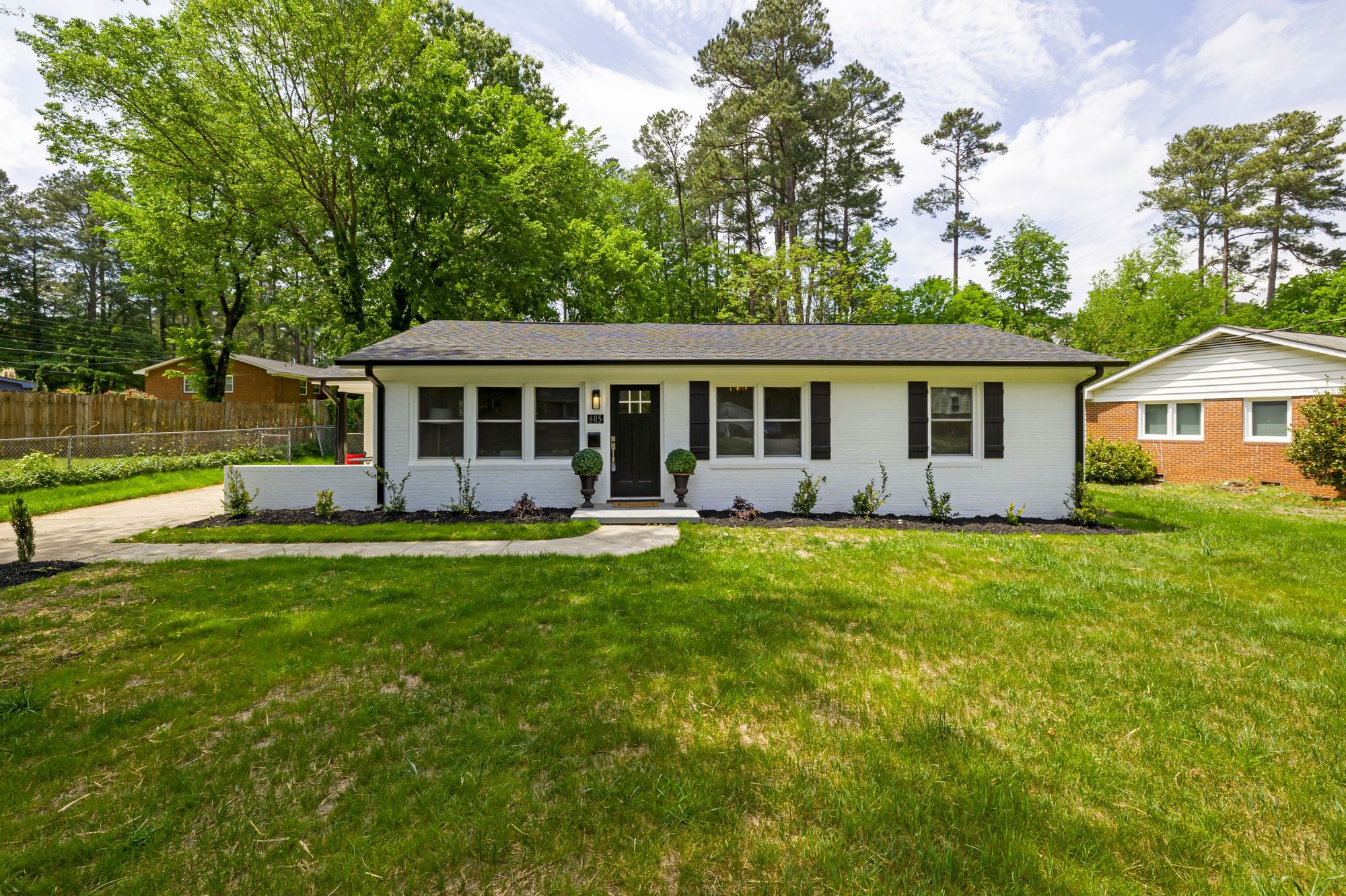 A single story suburban house with a front lawn and mature trees