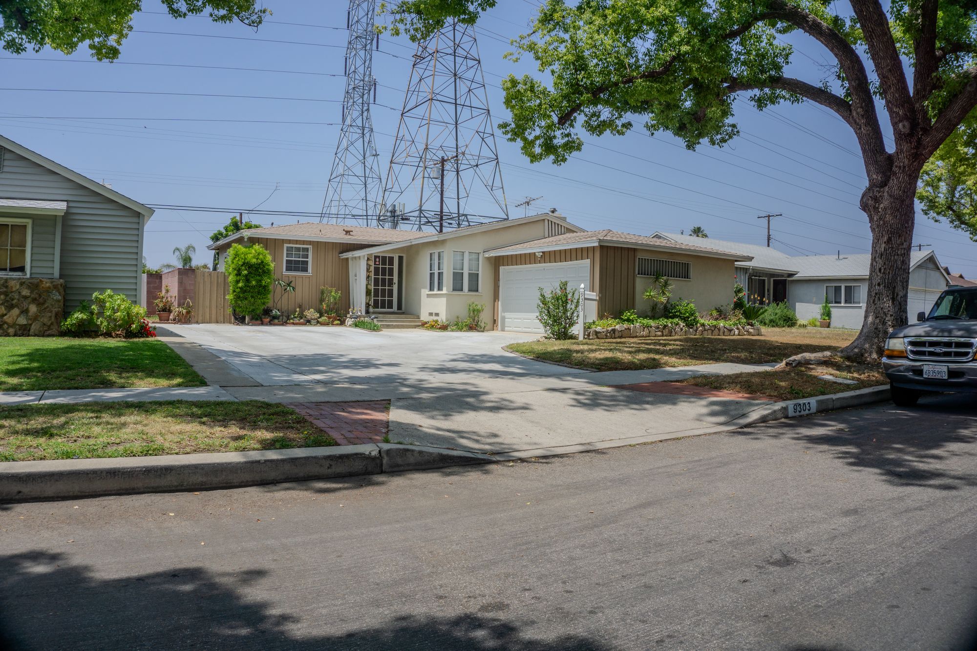 A suburban street of mid century homes and mature greenery on a sunny day