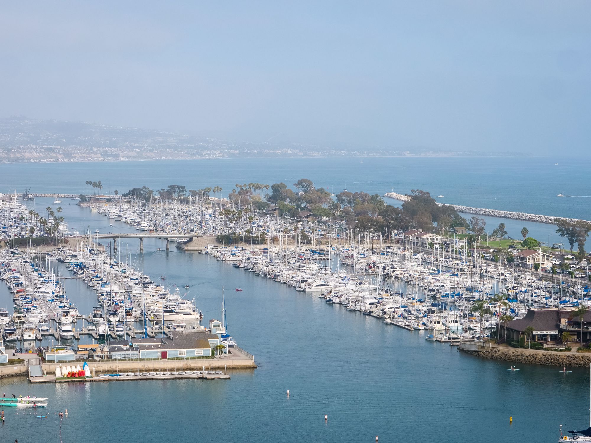 Aerial view of a yacht marina with blue water and the coastline beyond