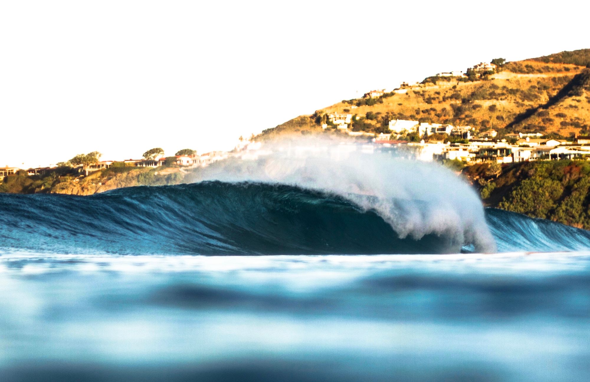 A wave breaking off the Southern California coast under clear skies