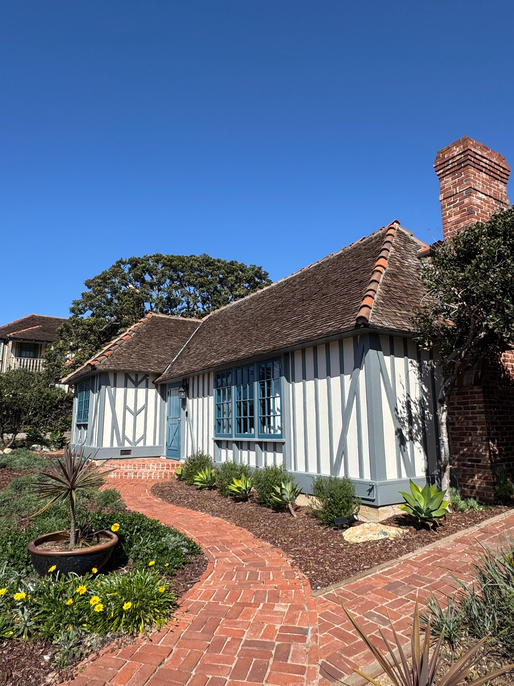 A cottage with a brick pathway under clear blue skies