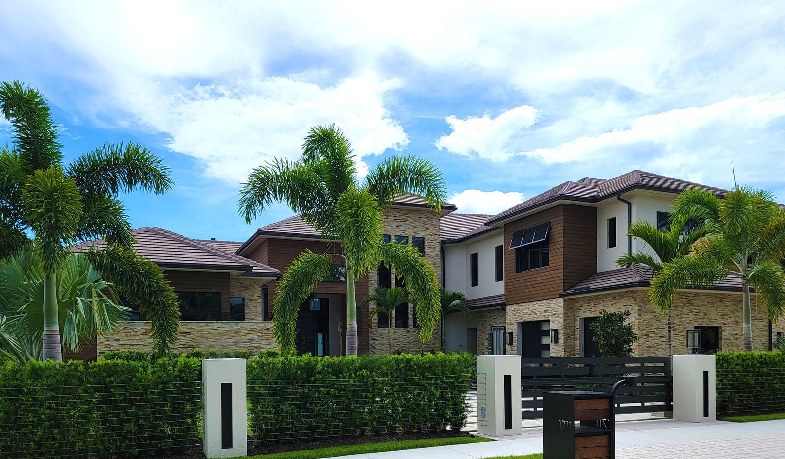 A low modern house set behind tall palm trees and mature planting that screen it from the street.