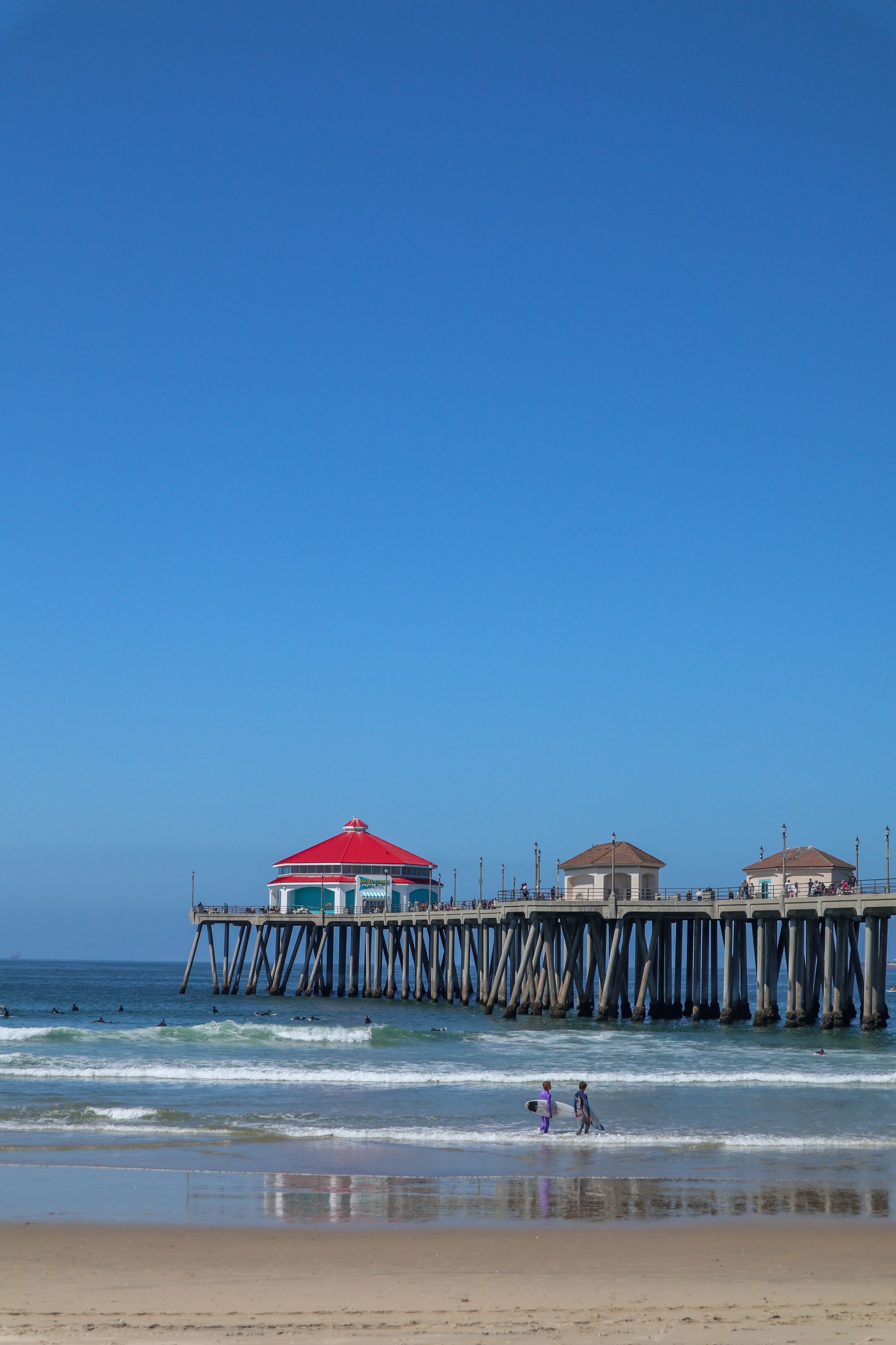 A long pier reaching into the Pacific Ocean under a clear blue sky